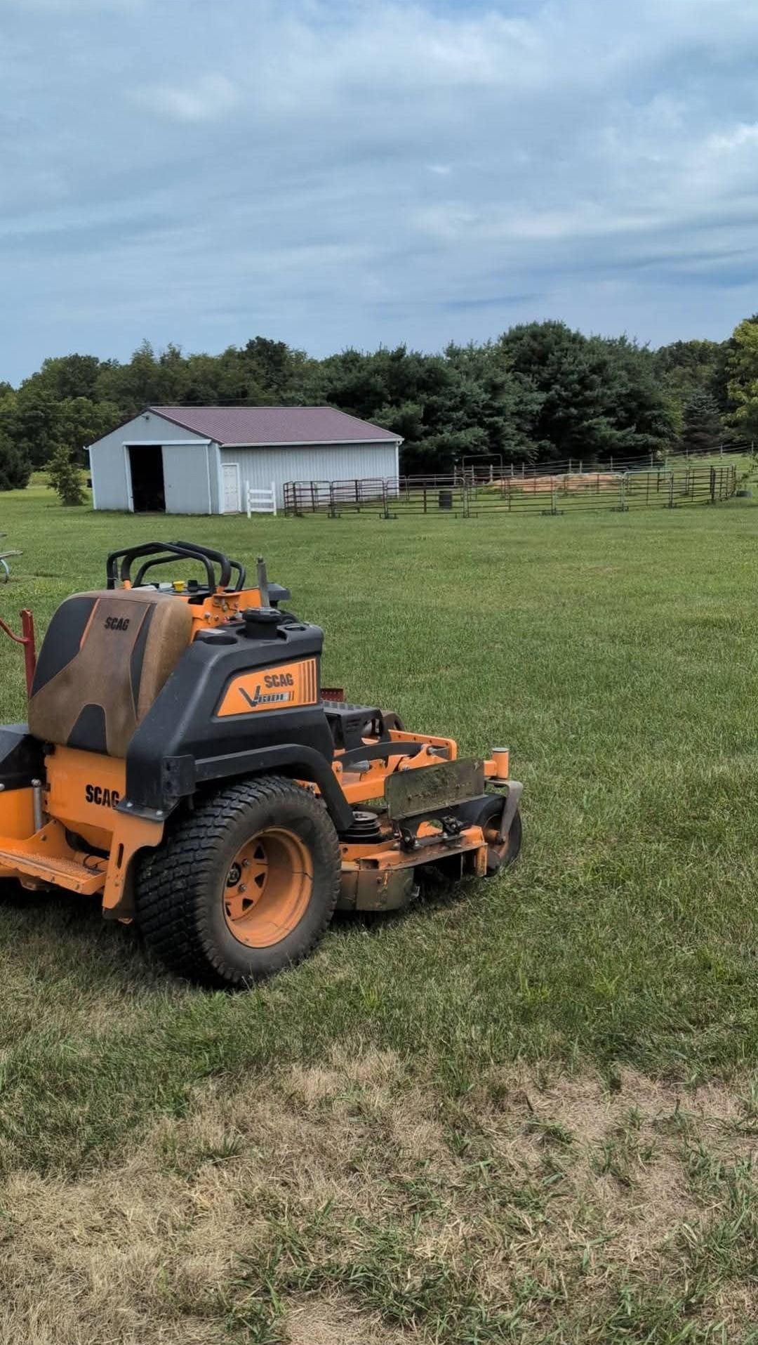 The SCAG mower on a lawn beside a barn