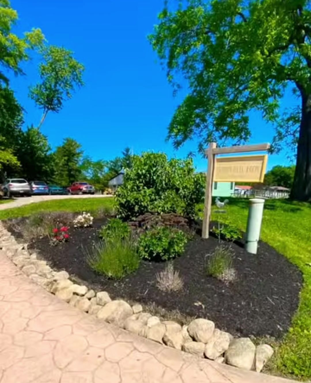 A stone-edged flower bed with fresh mulch beside a sign